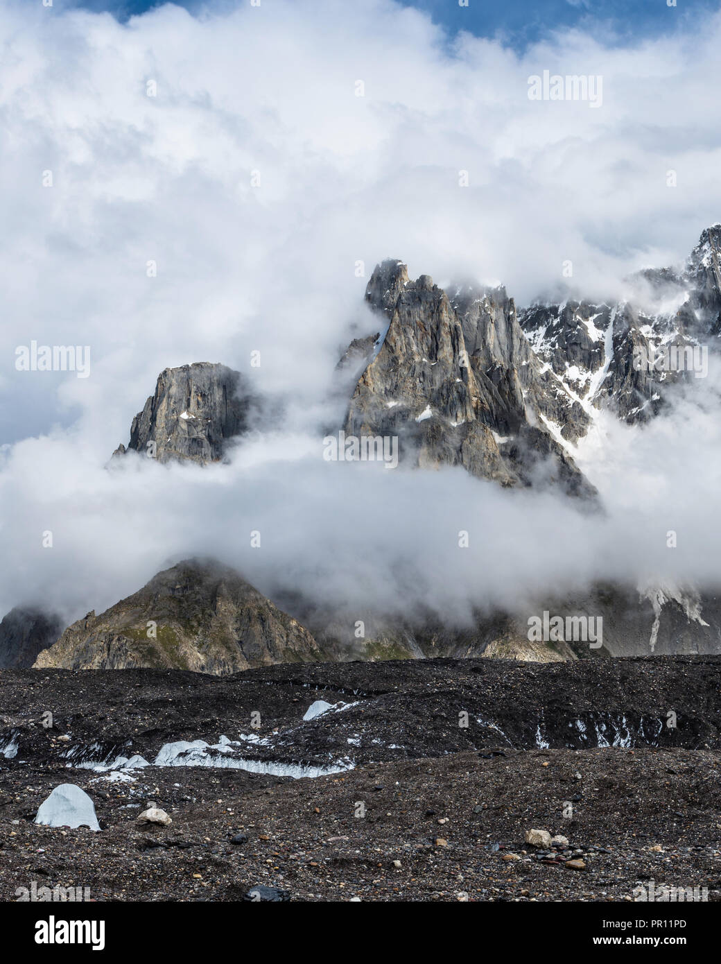 Jagged peaks from Biarchedi group of mountains appear behind clouds, Baltoro Galcier, Karakoram, Pakistan Stock Photo