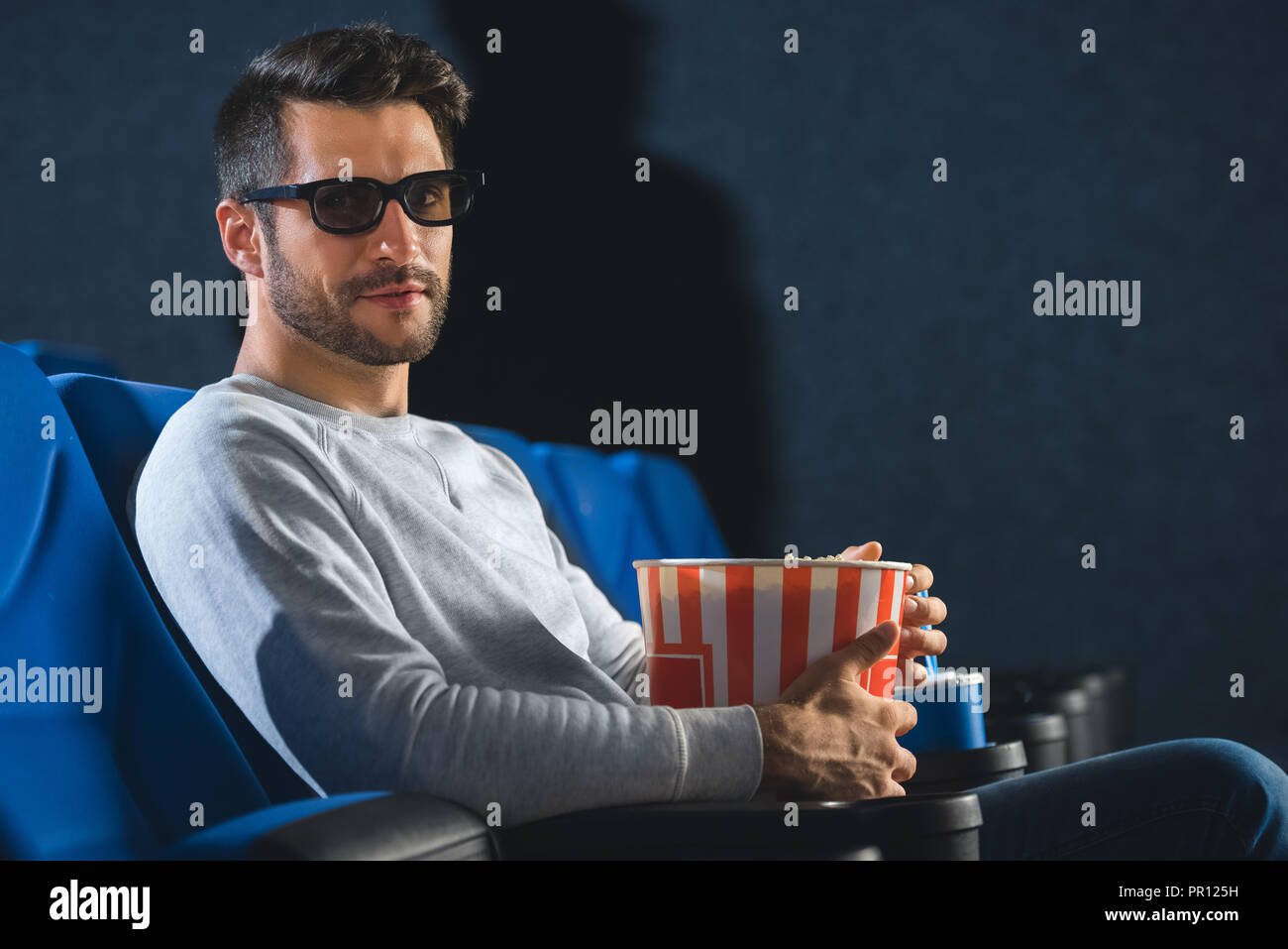 side view of young man in 3d glasses with popcorn in cinema Stock Photo