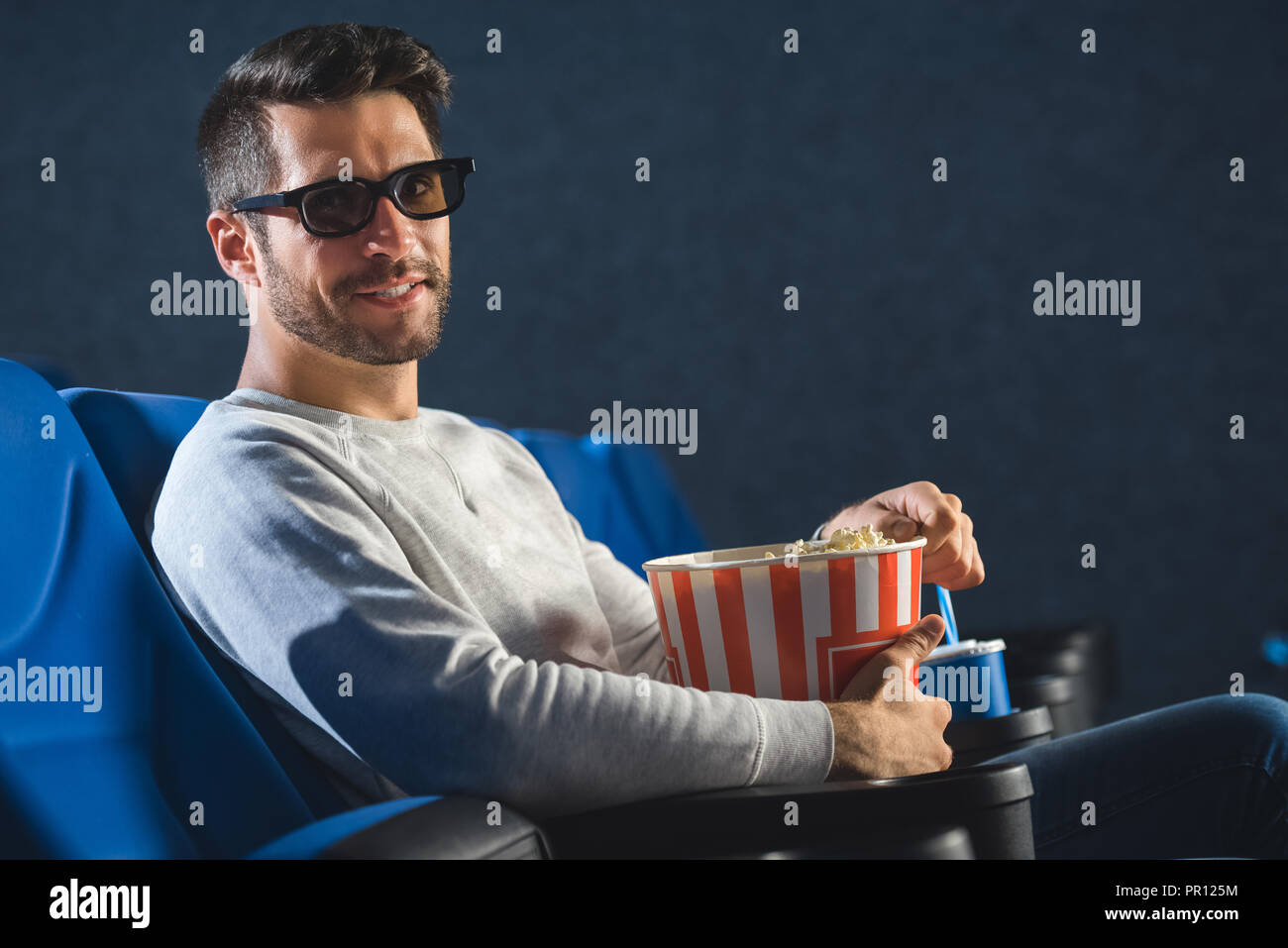 side view of smiling man in 3d glasses with popcorn in cinema Stock Photo