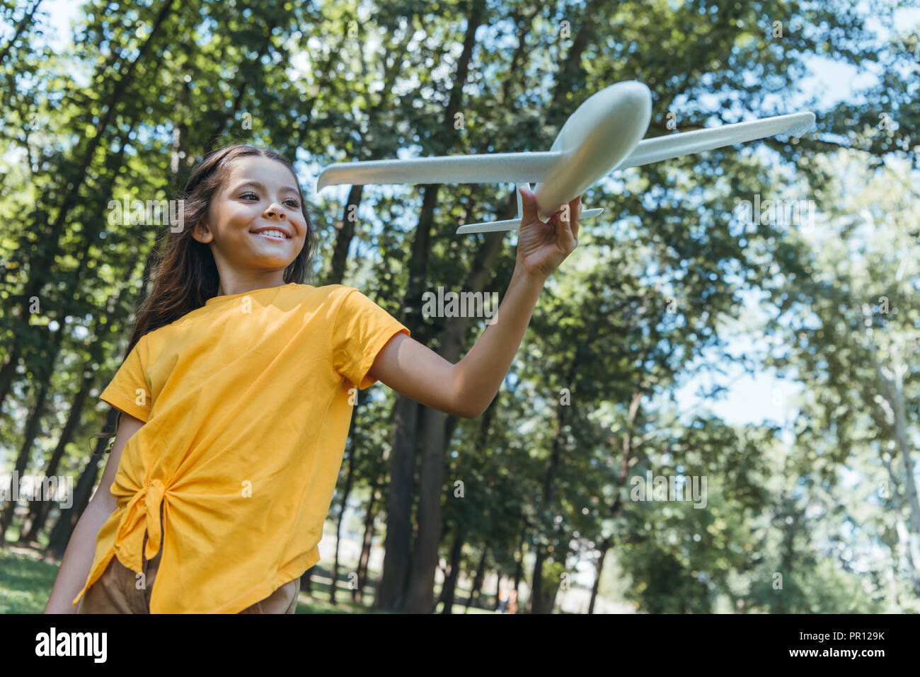low angle view of cute happy child holding toy plane in park Stock Photo