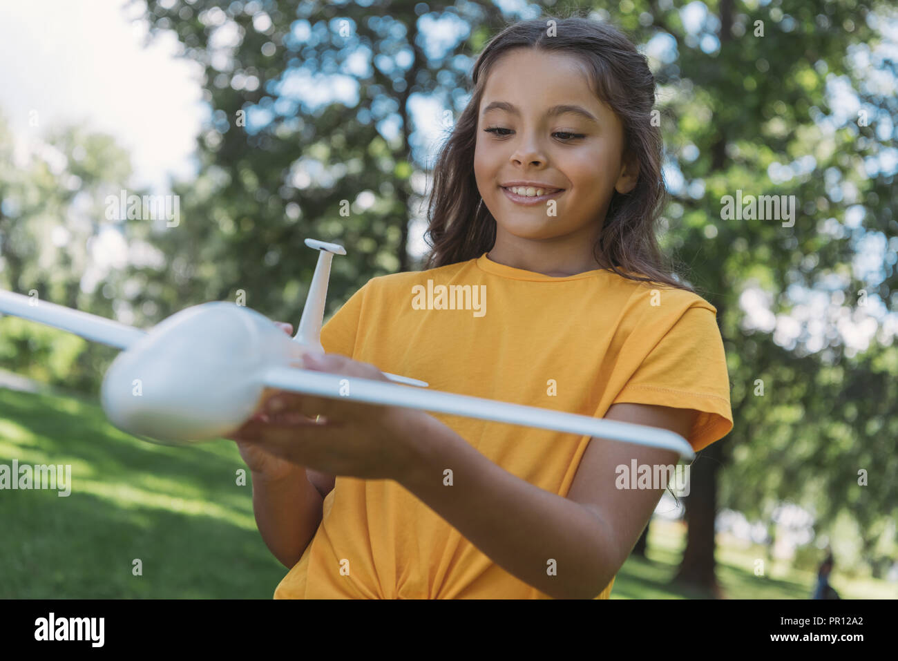 close-up view of cute smiling child holding toy plane model in park Stock Photo