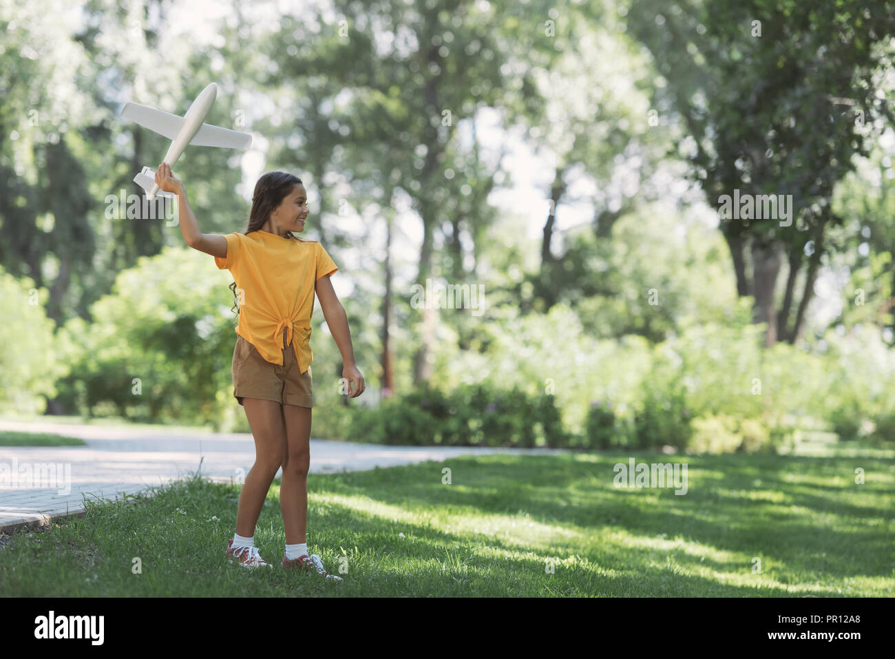 beautiful happy child playing with toy plane in park Stock Photo