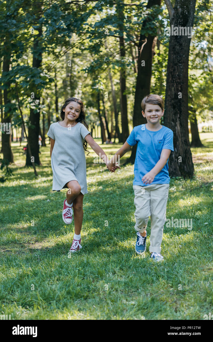 adorable happy kids holding hands and running together in park Stock ...