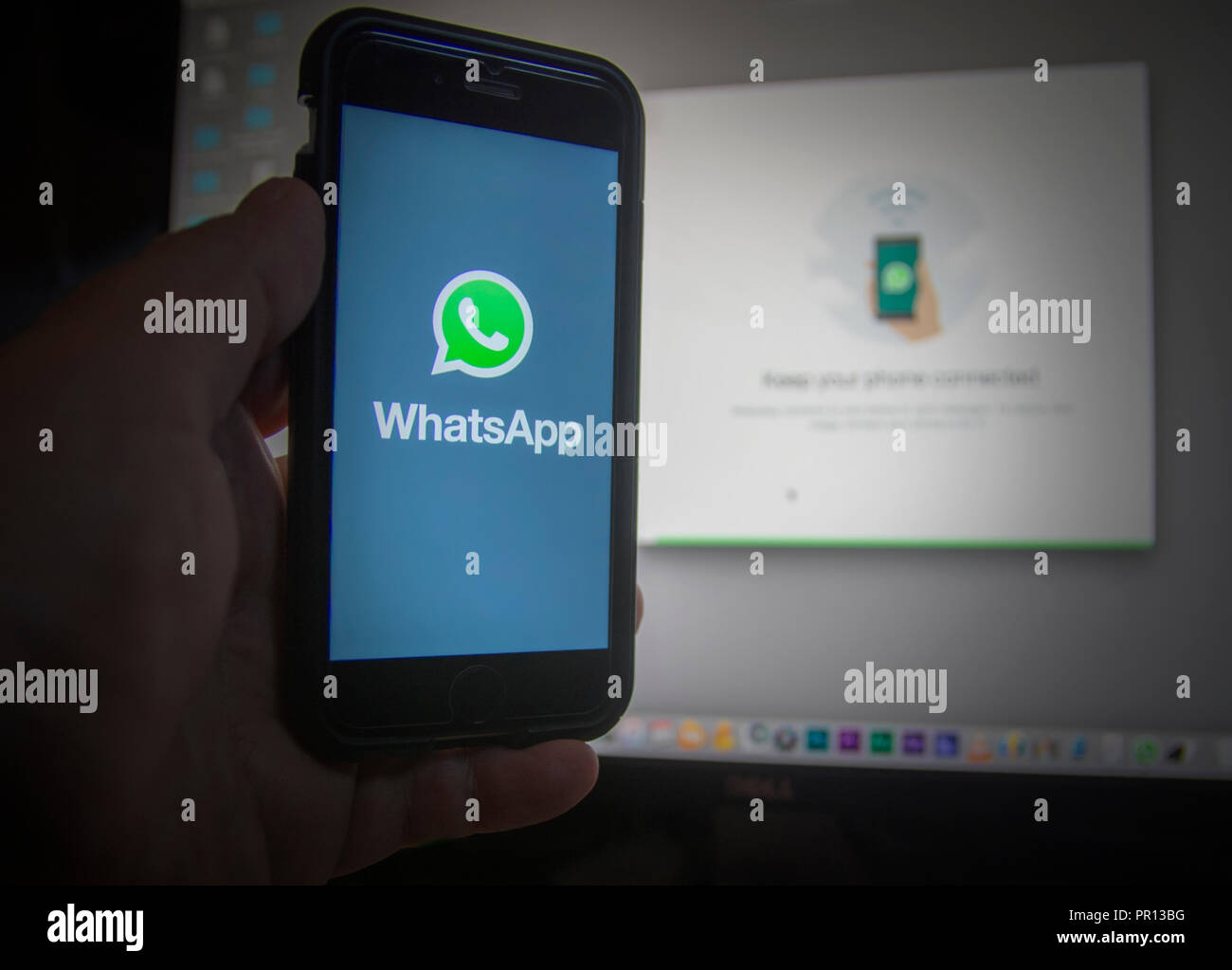 Mobile phone communicating with an office computer using Whatsapp application Stock Photo
