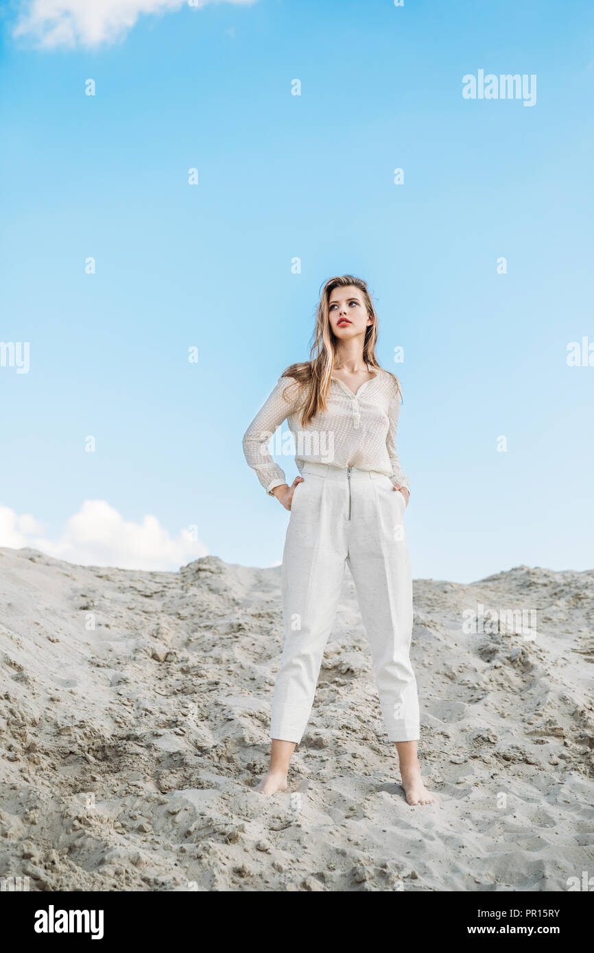 attractive fashionable woman in white clothes posing on sand dune Stock ...