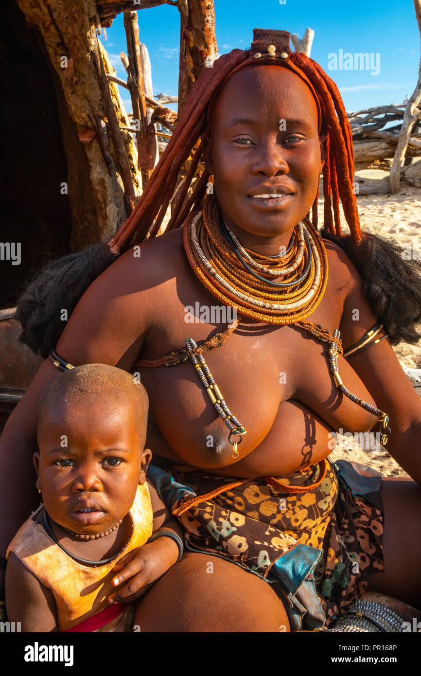 Red ochred, bare breasted Himba woman in traditional dress, with her child, Puros Village, near Sesfontein, Namibia, Africa Stock Photo