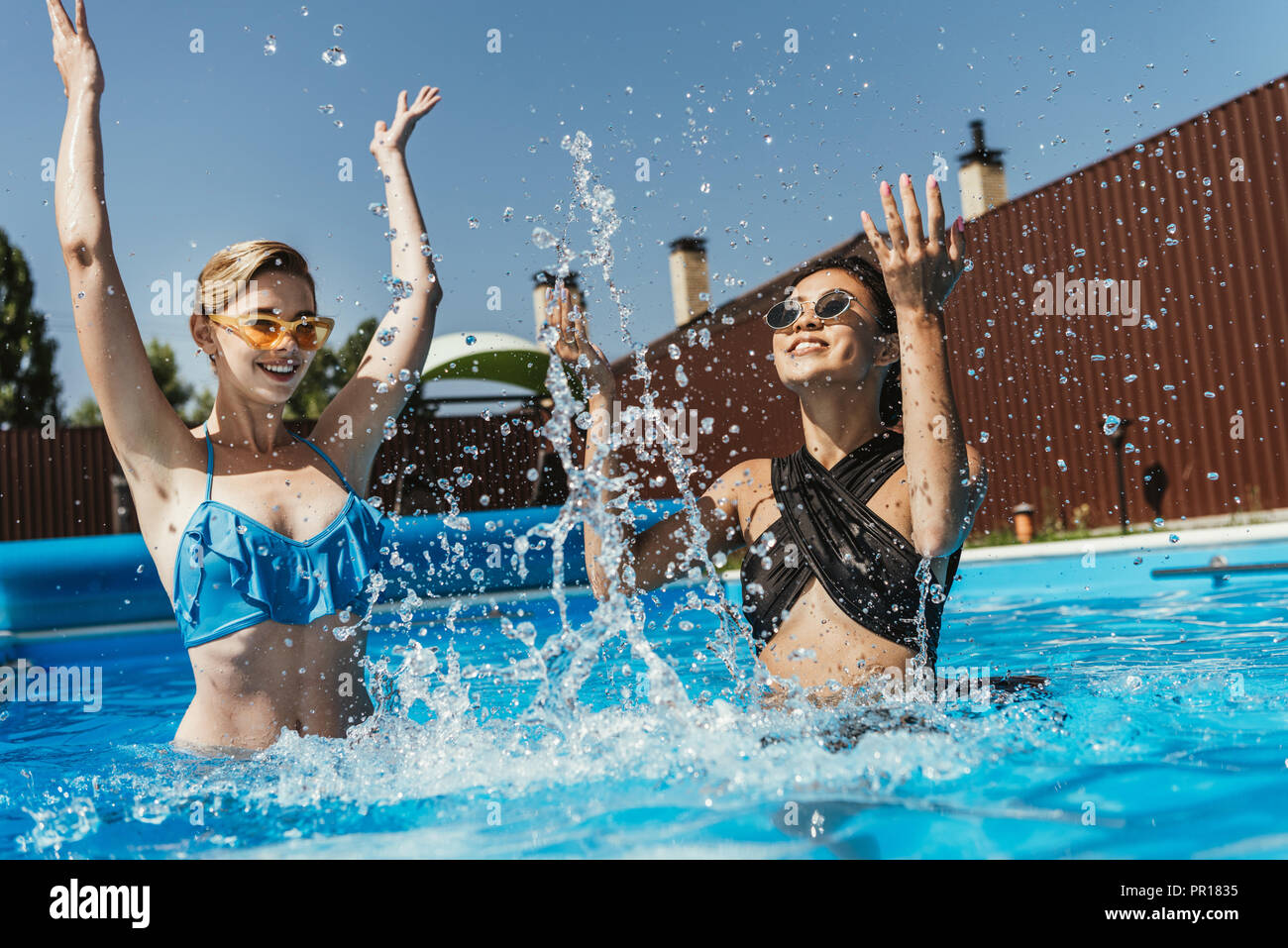 multicultural girls jumping in swimming pool Stock Photo