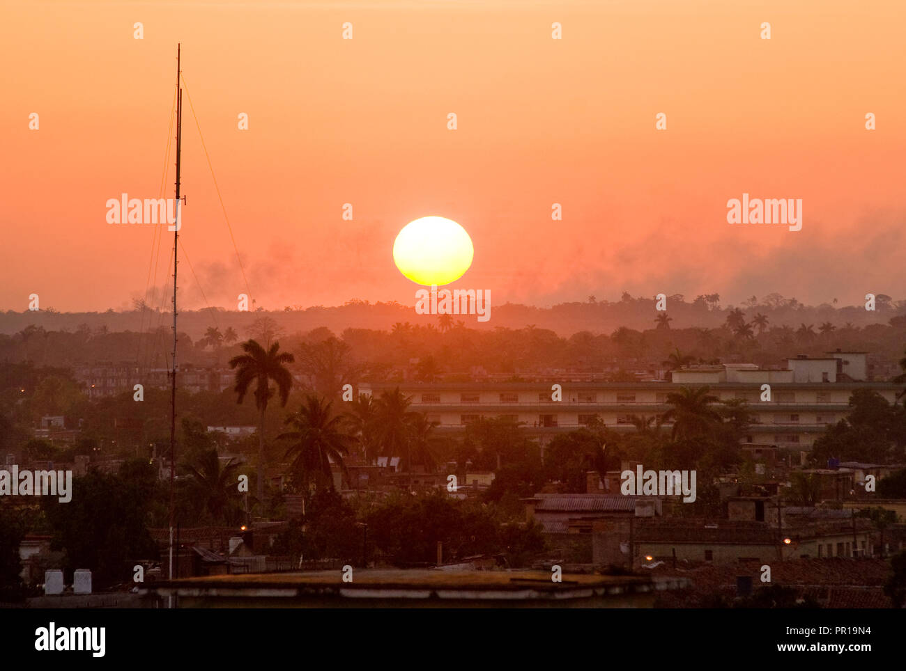 Red sun setting on polluted Camaguay's city Sunset in Cuba Stock Photo