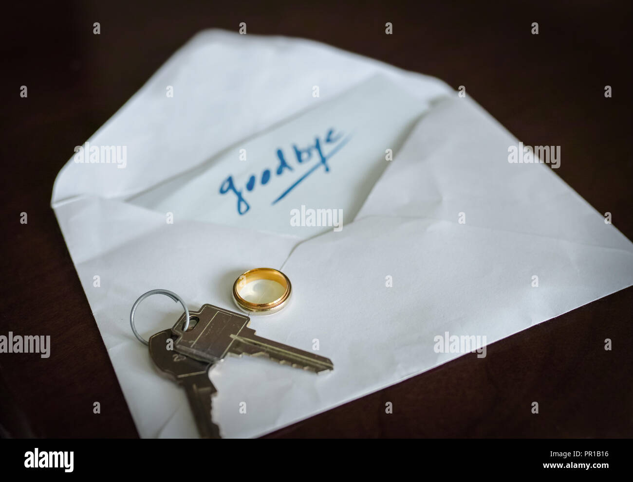 On the table, she or he, left the keys, the wedding ring and a envelope with this word: Goodbye Stock Photo