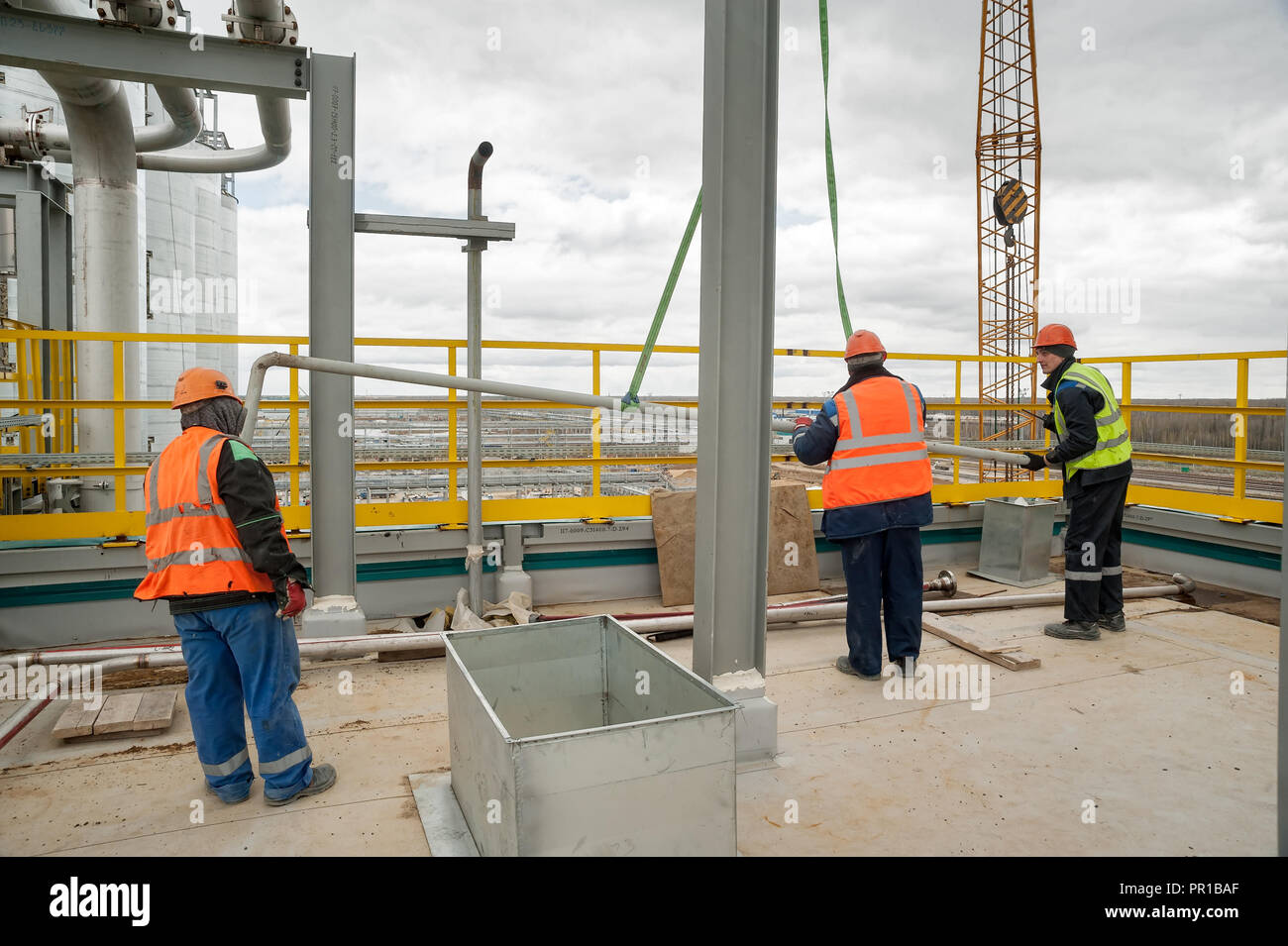 Construction workers placing pipe lifted by crane Stock Photo Alamy