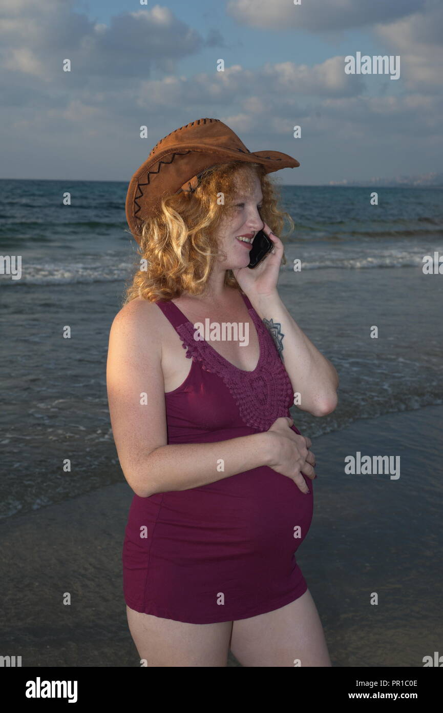 redhead pregnancy lady talks with cellular Stock Photo