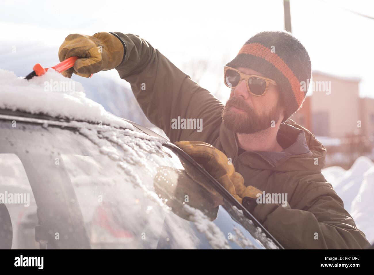 Man cleaning snow from car windshield Stock Photo