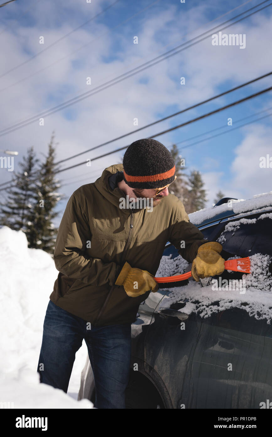 Man cleaning snow from car windshield Stock Photo