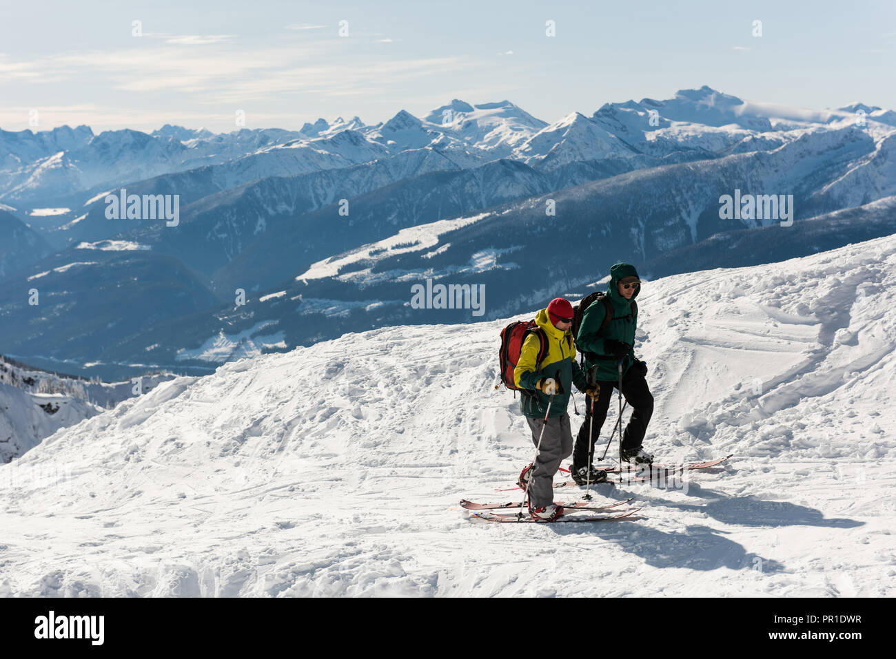 Male and female skiers walking on a snowy mountain Stock Photo