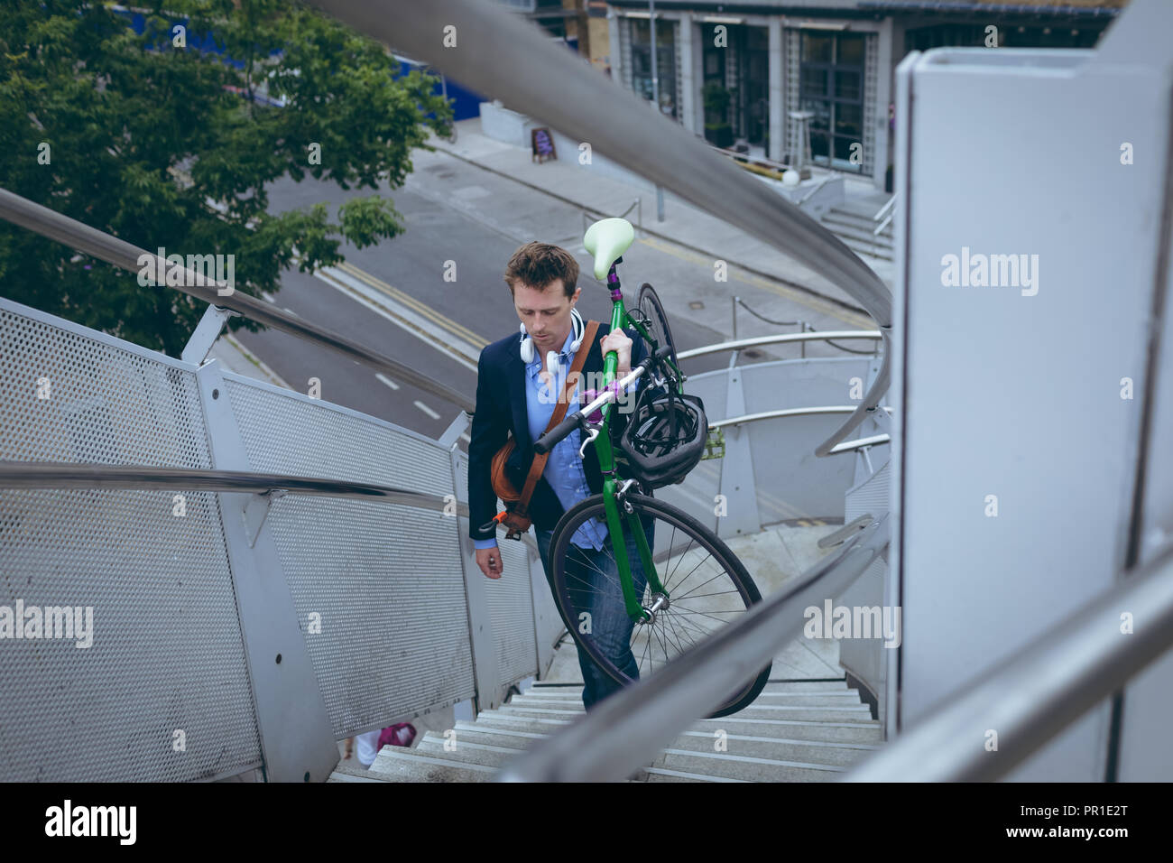 Businessman walking up stairs with bicycle Stock Photo