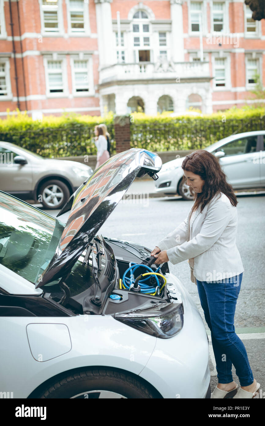 Businesswoman charging electric car at charging station Stock Photo
