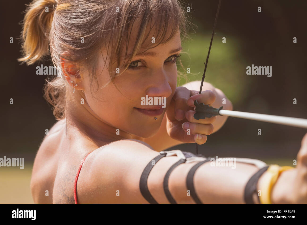 Woman practicing archery at boot camp Stock Photo