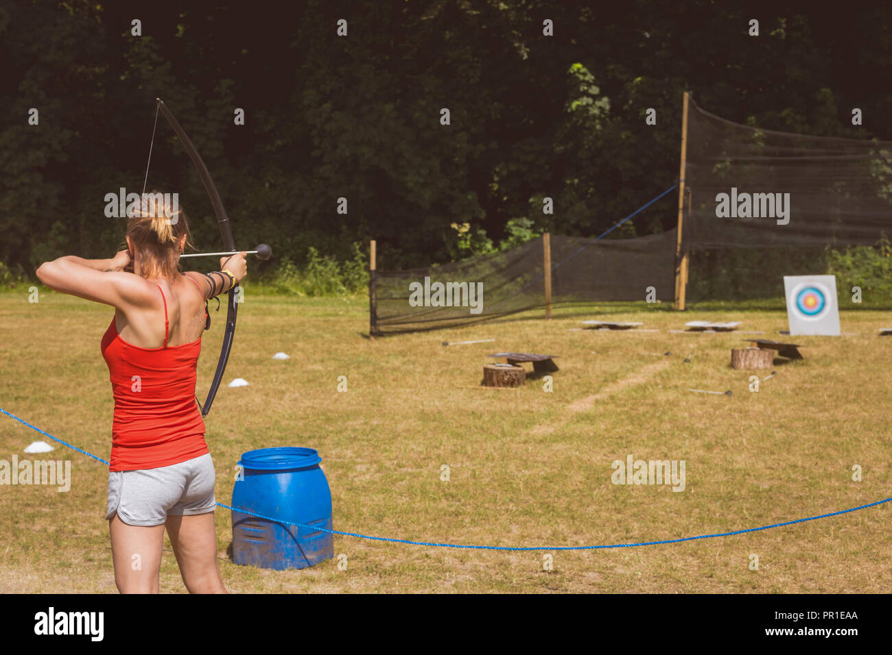 Woman practicing archery at boot camp Stock Photo