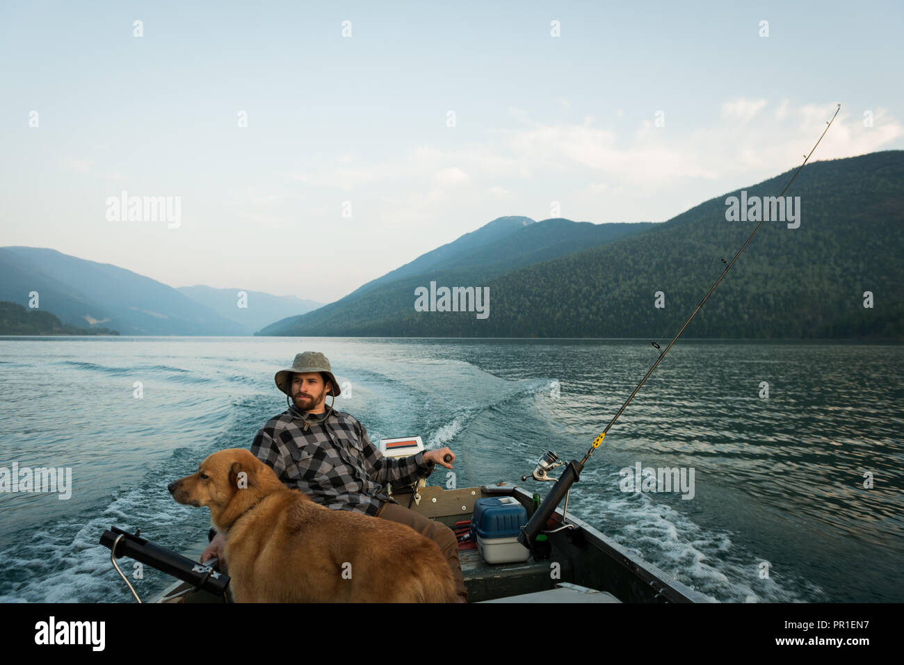 Fisherman fishing with his dog in the river Stock Photo