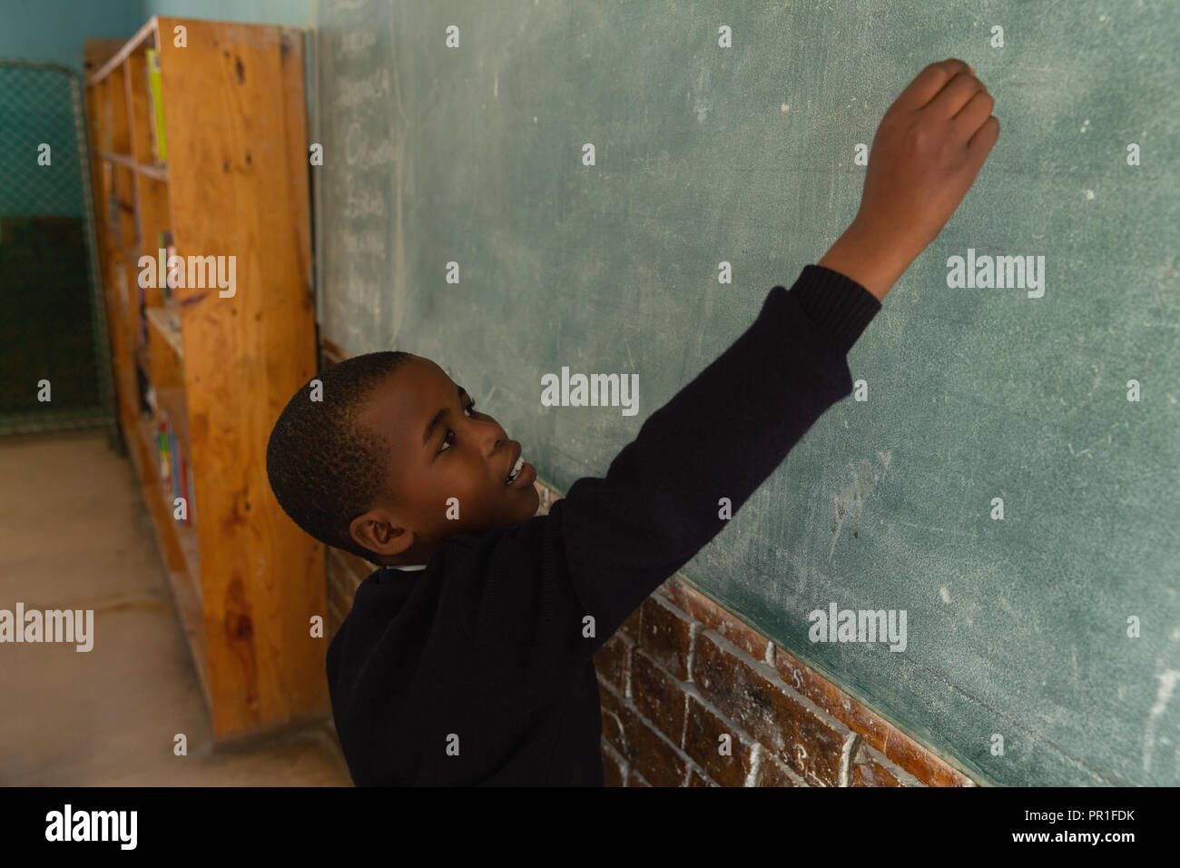 Schoolboy writing on chalkboard in classroom Stock Photo - Alamy