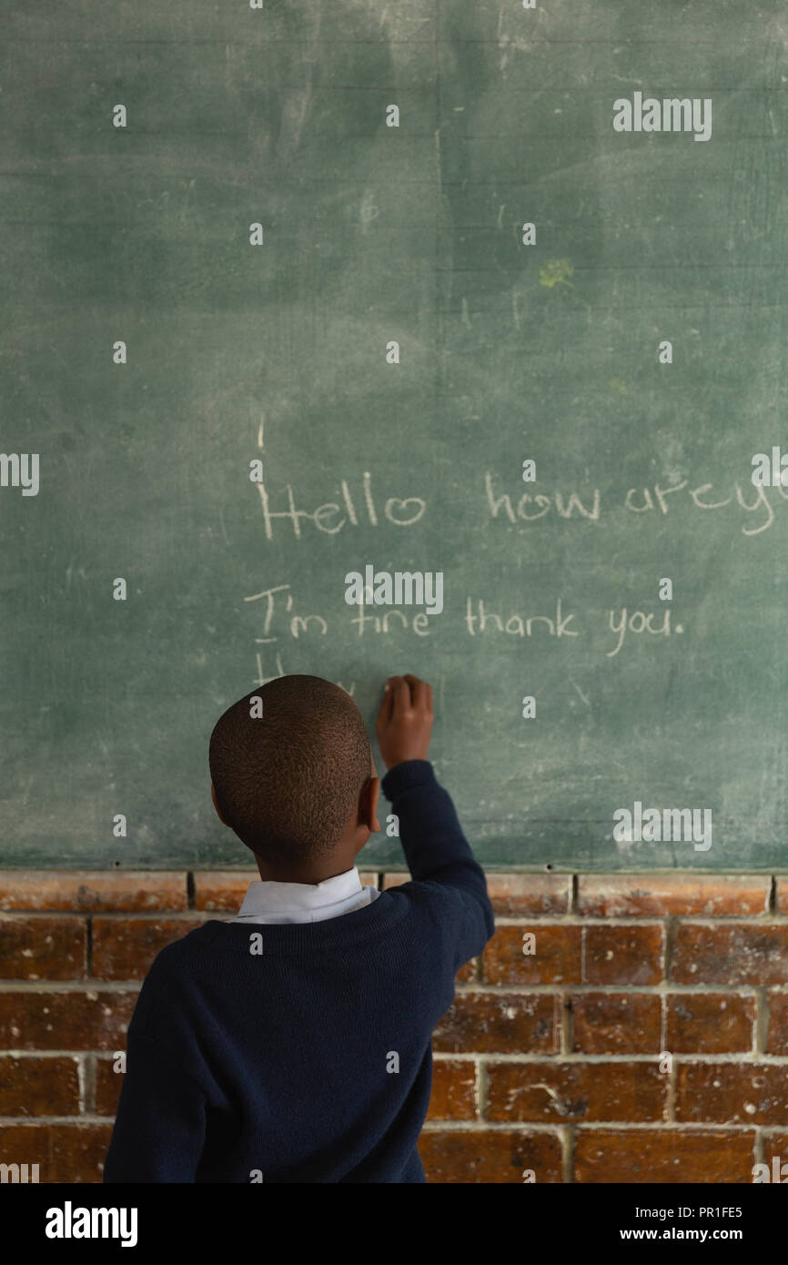 Schoolboy writing on chalkboard in classroom Stock Photo - Alamy