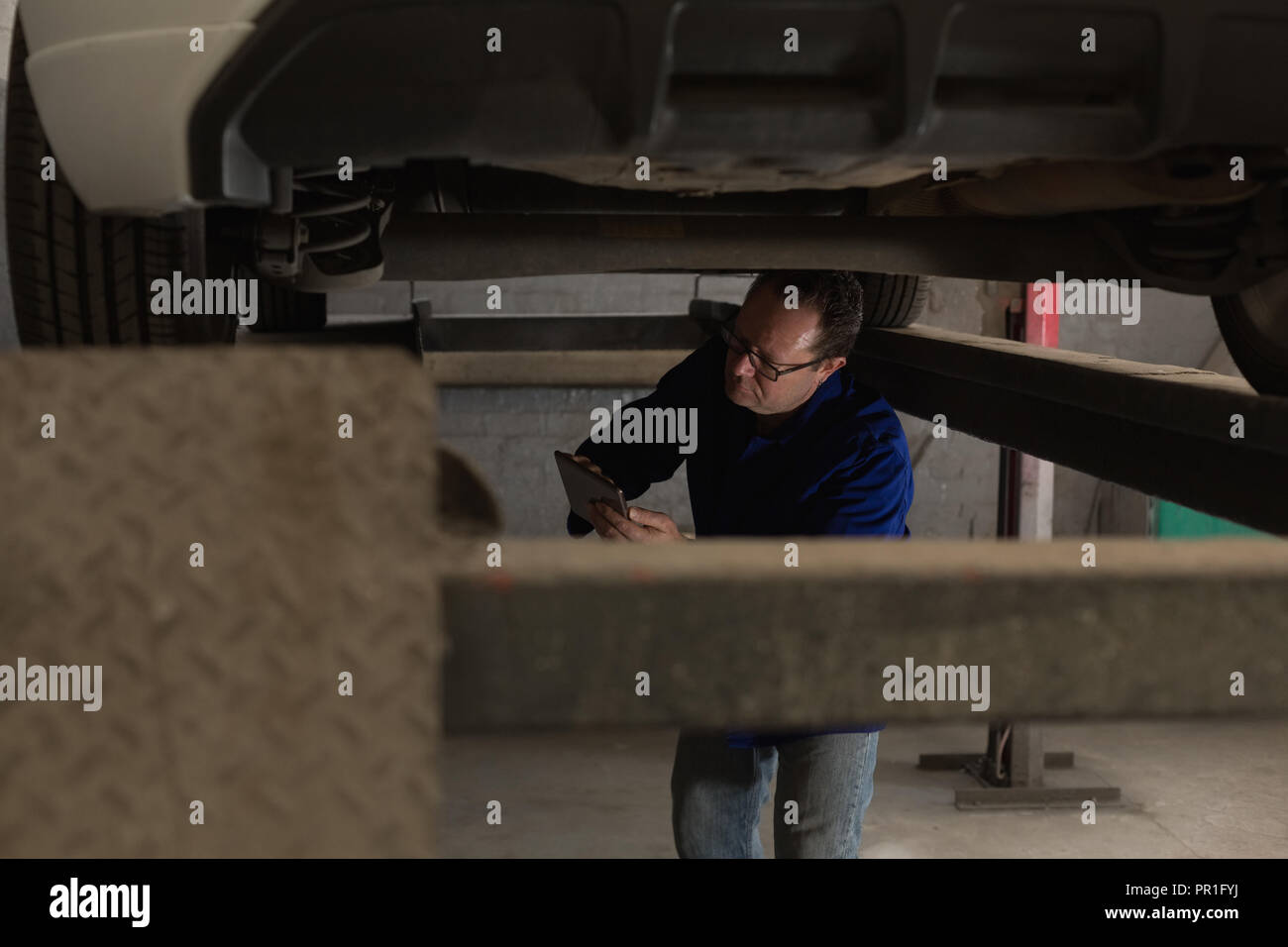 Mechanic using digital tablet while servicing a car Stock Photo