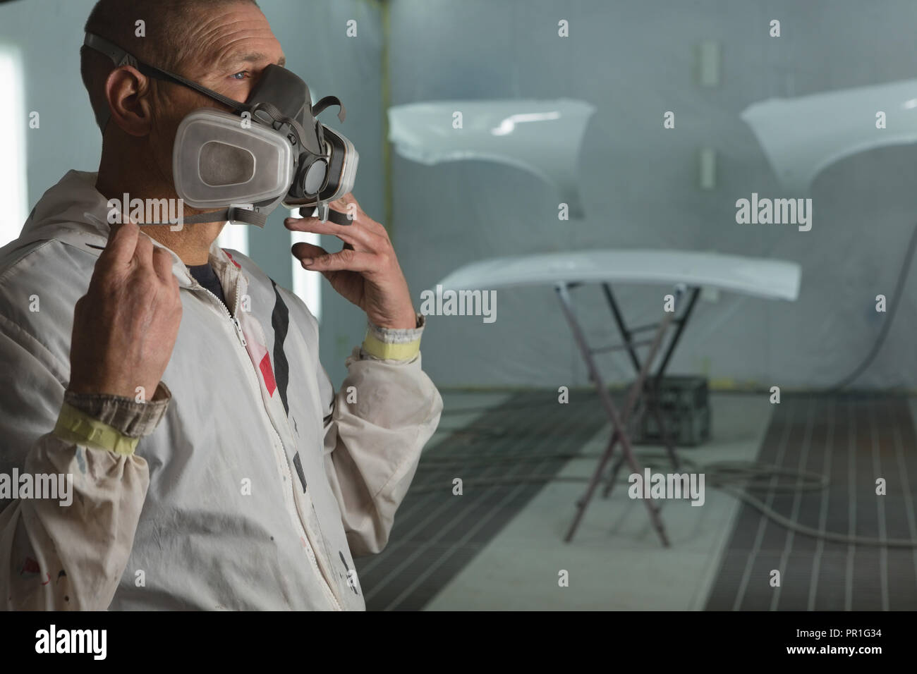 Mechanic wearing gas mask in garage Stock Photo