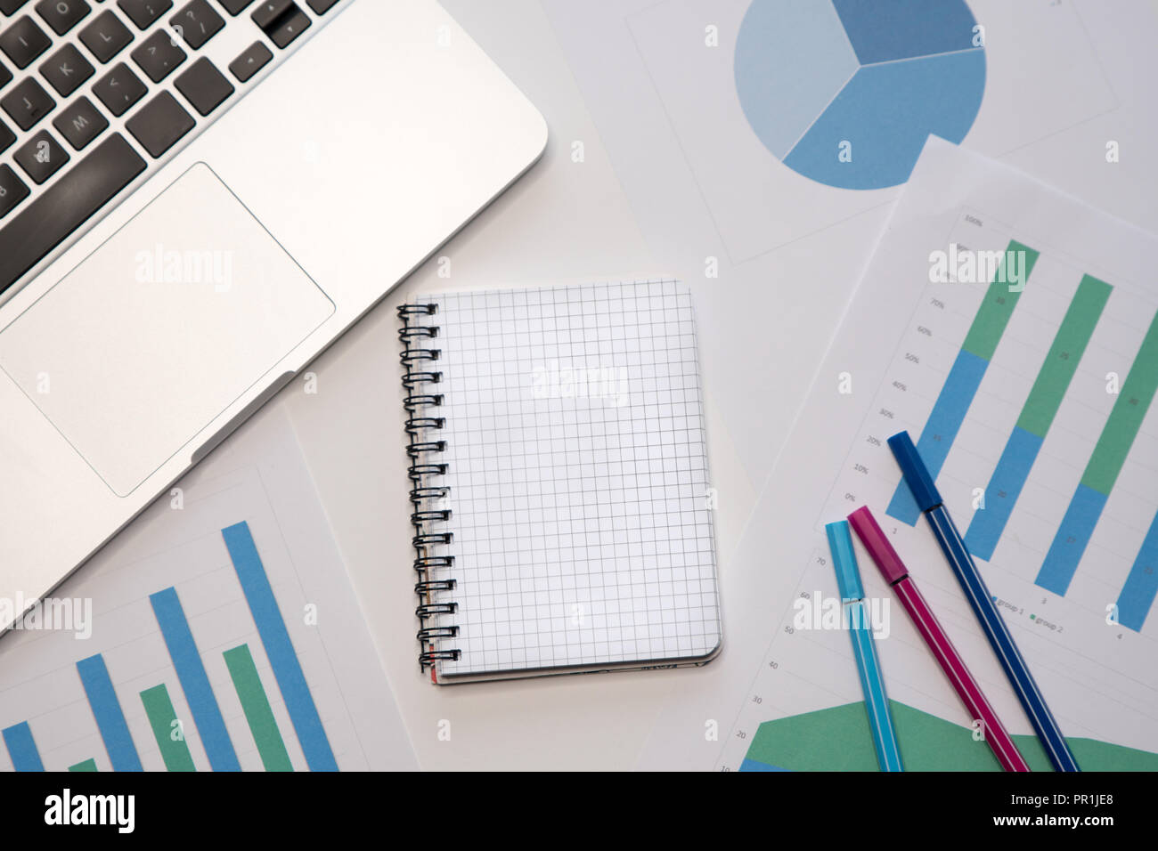 Modern workspace with blank notepad, laptop, pens on desktop. Top view ...