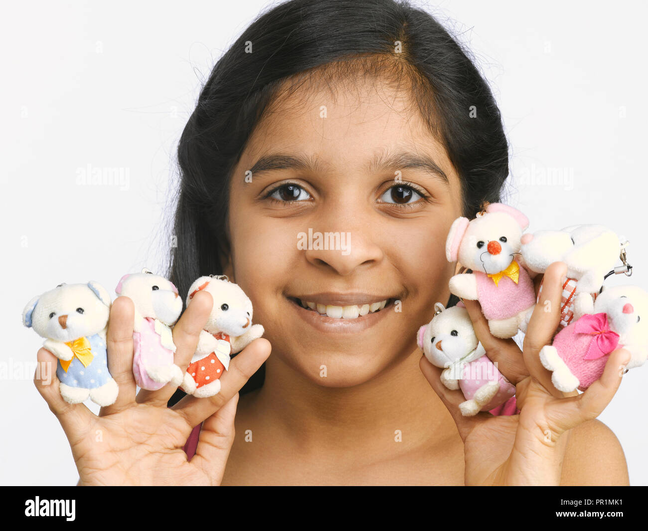 Young girl holding and playing with cute soft toys. Shot against a