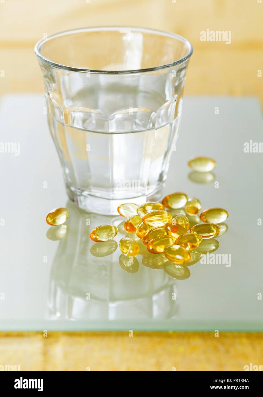 https://c8.alamy.com/comp/PR1RNA/evening-primrose-oil-capsules-in-a-pile-next-to-a-glass-of-water-PR1RNA.jpg