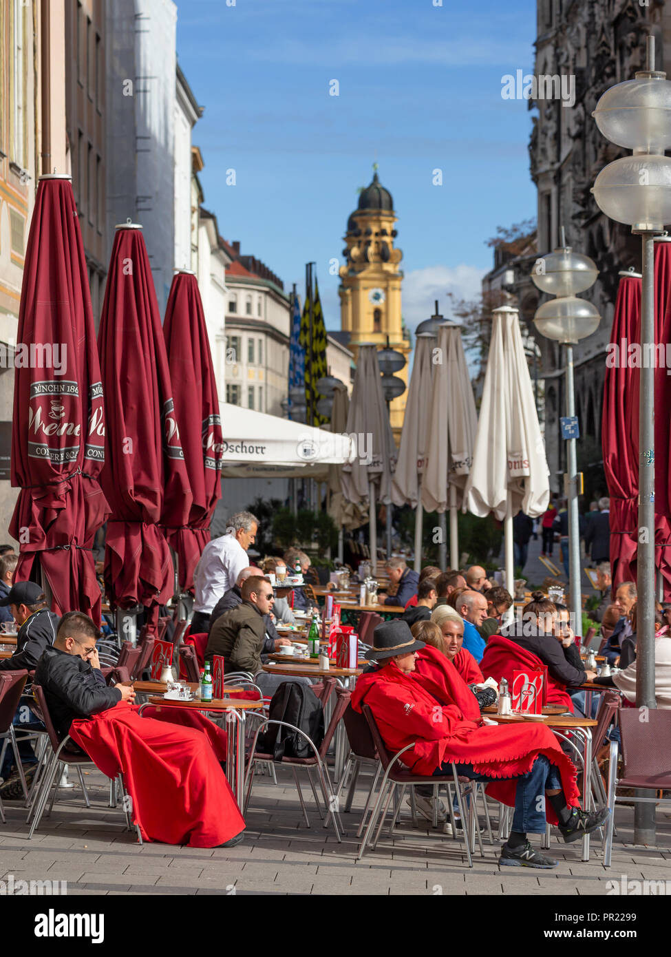 Guests of an outdoor café at Marienplatz in Munich, Germany enjoy late summer sunshine with Theatinerkirche in the background Stock Photo