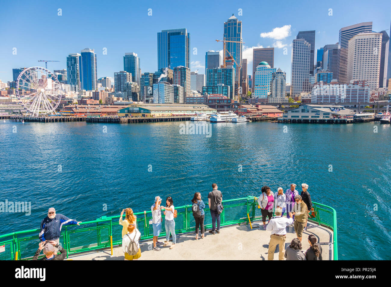 Seattle Washington city skyline with passengers in foreground on deck of passenger ferry in Puget Sound headed to Seattle Washington Stock Photo
