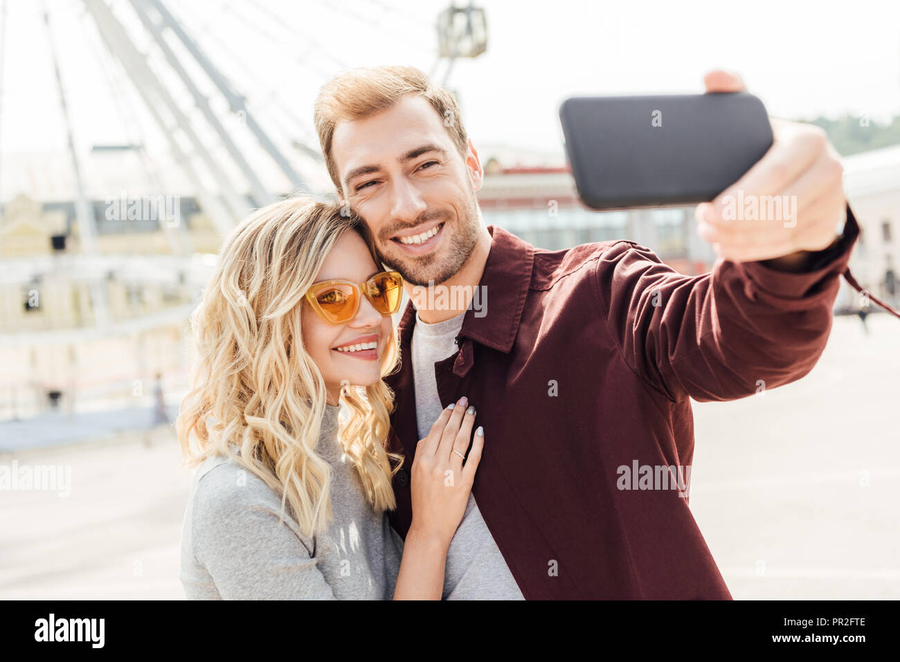 smiling couple in autumn outfit taking selfie with smartphone in city Stock Photo