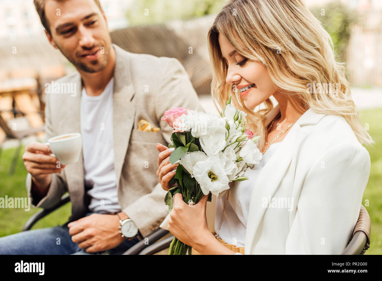 attractive girlfriend sniffing bouquet of roses in cafe Stock Photo