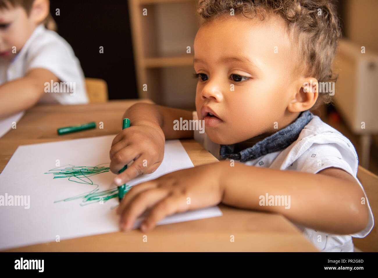 adorable african american boy drawing with green felt tip pen in ...