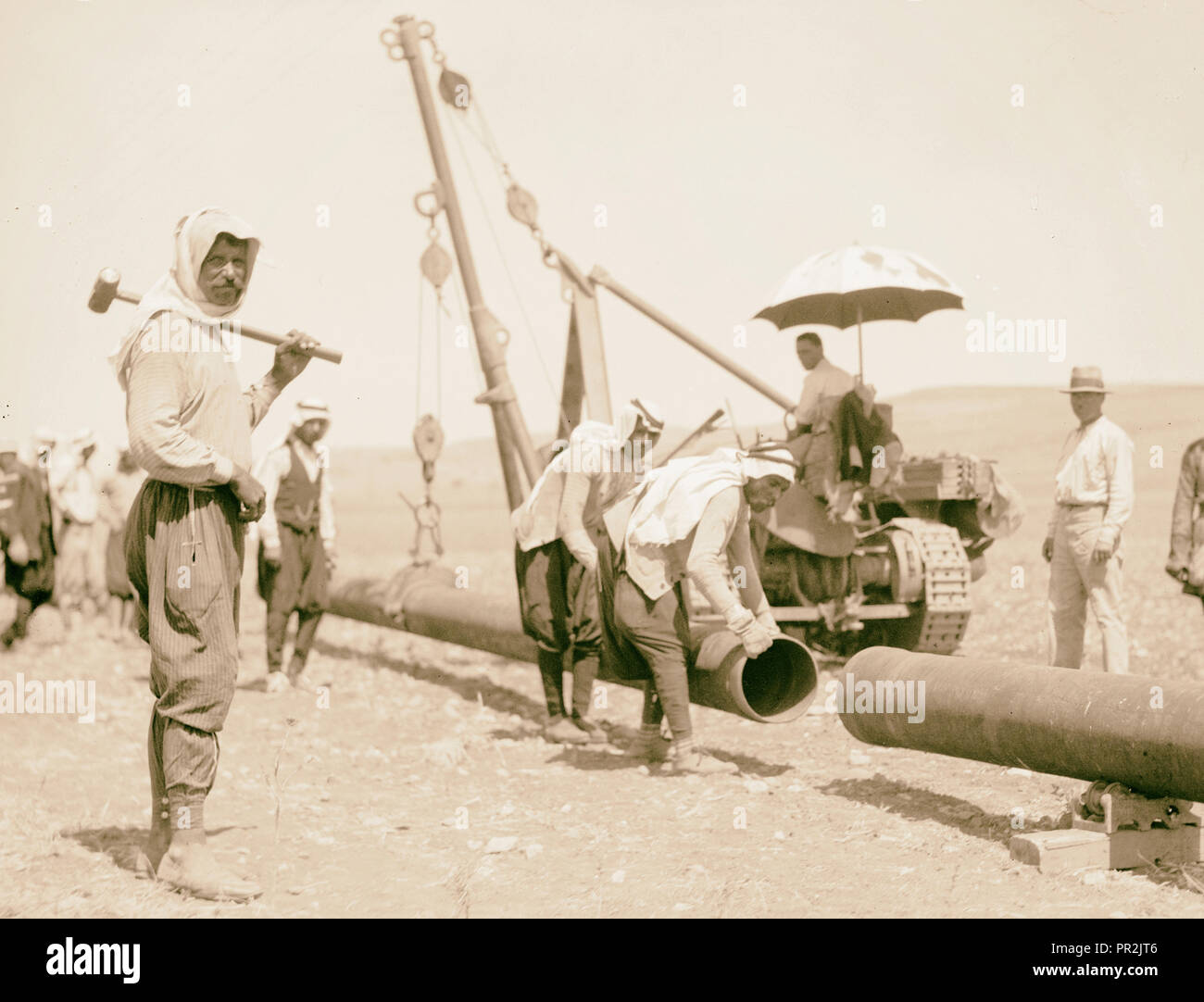 Laying of the Iraq Petroleum Company's pipe line across the Plain of Esdraelon, July 1933. Swinging pipes into place. Tractor Stock Photo