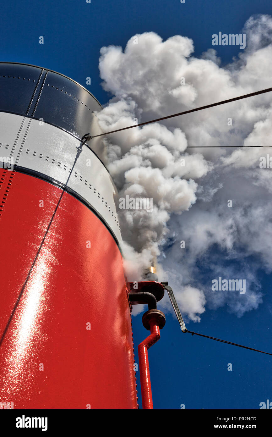 Closeup of a steamboat whistle blowing out white steam from the stack and a clear blue sky in the background Stock Photo