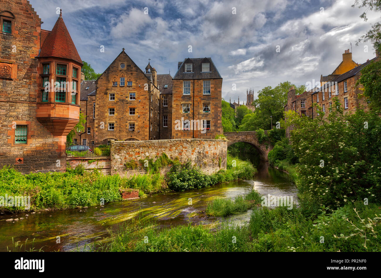 Quaint stream with green flora along it flowing through Dean Village in Edinburgh with old Scottish buildings Stock Photo