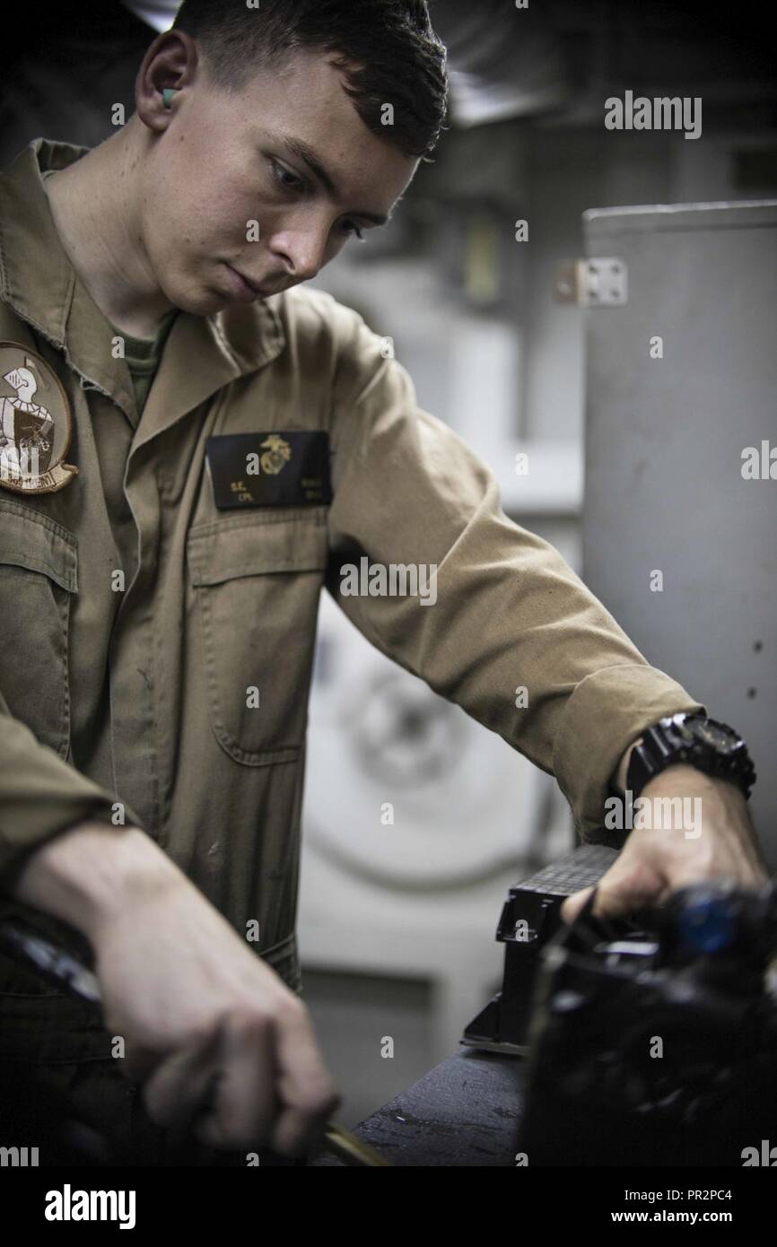 5TH FLEET AREA OF OPERATIONS (July 22, 2017) Cpl. Spencer Bonds cleans the cooling coils of a heat exchanger for an MV-22B Osprey aboard the amphibious assault ship USS Bataan (LHD 5). The ship and its ready group are deployed in the U.S. 5th Fleet area of operations in support of maritime security operations to reassure allies and partners, and preserve the freedom of navigation and the free flow of commerce in the region. Stock Photo