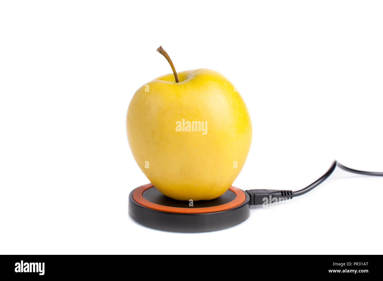 Yellow apple lies on a platform for wireless charging on an isolated white background Stock Photo