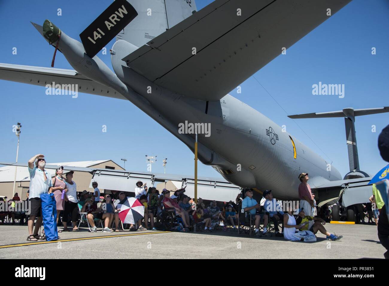 Service members and members from the local community sit under a KC-135 Stratotanker as they watch the performers perform during the SkyFest 2017 Air Show and Open House at Fairchild Air Force Base, Washington, July 29, 2017. SkyFest was an opportunity to give the local and regional community a chance to view Airmen and our resources. Stock Photo