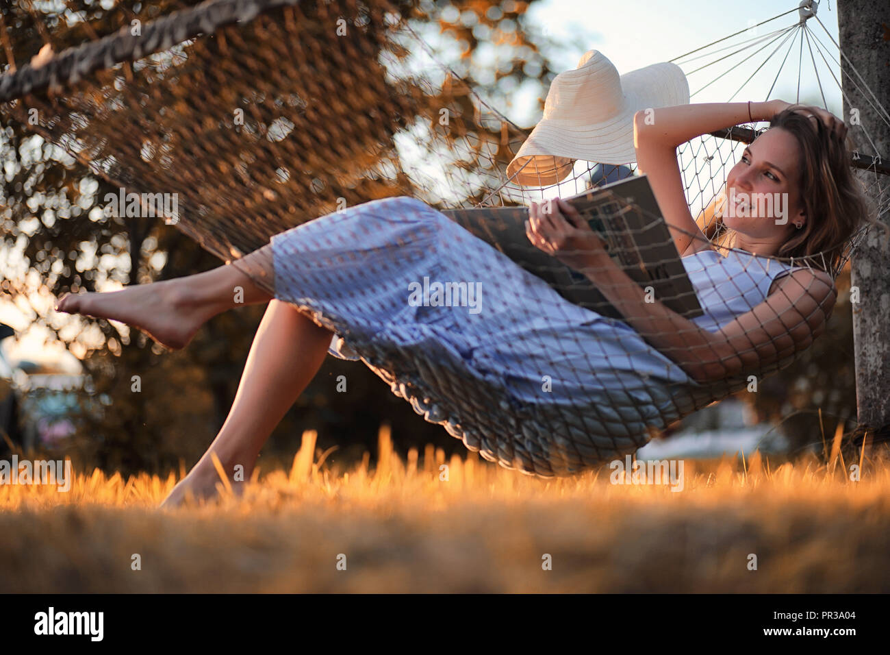 Beautiful girl in hammock reading a book Stock Photo - Alamy