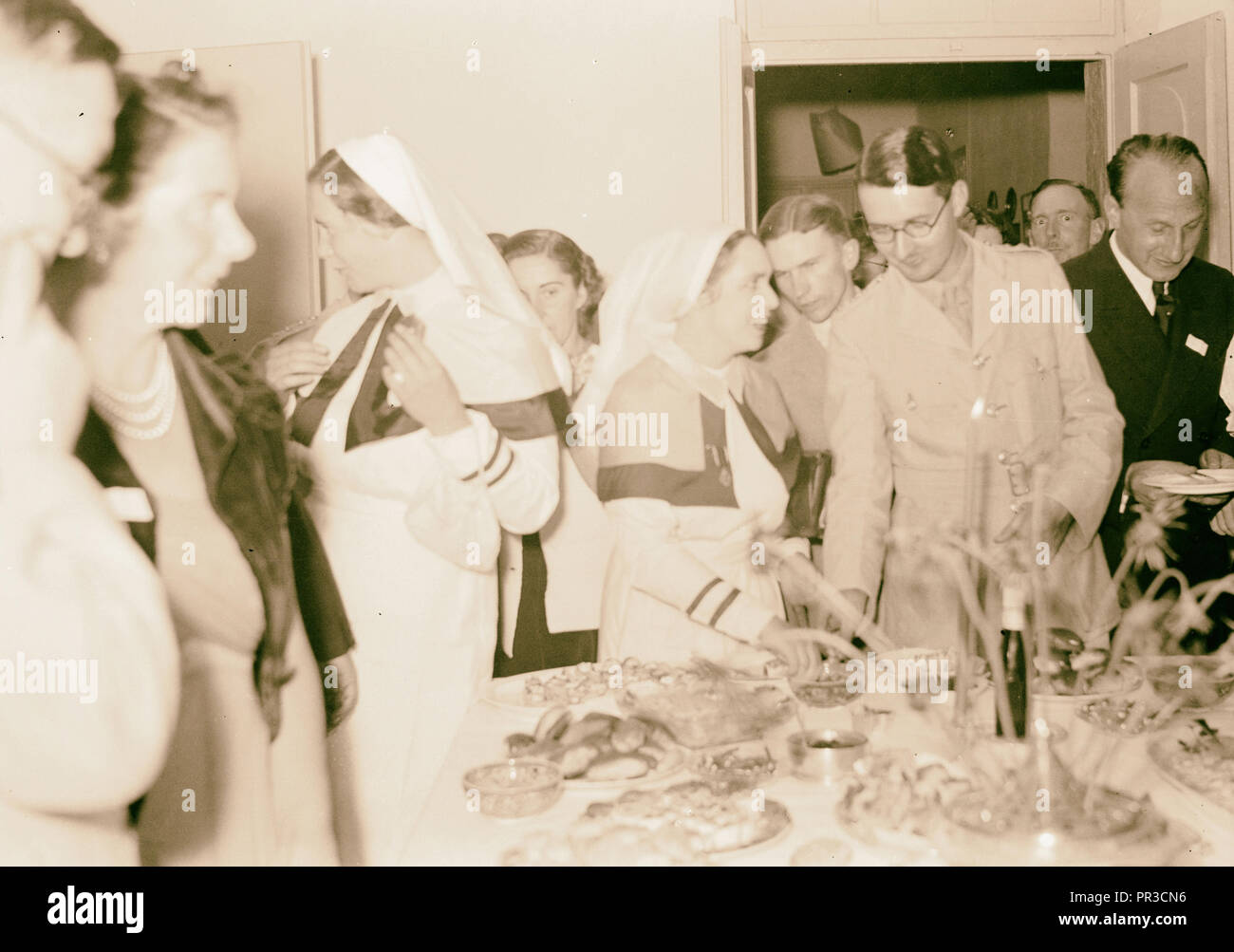 Dance in Dr. & Mrs. Wren's house Nurses & other guests around buffet table, Israel Stock Photo