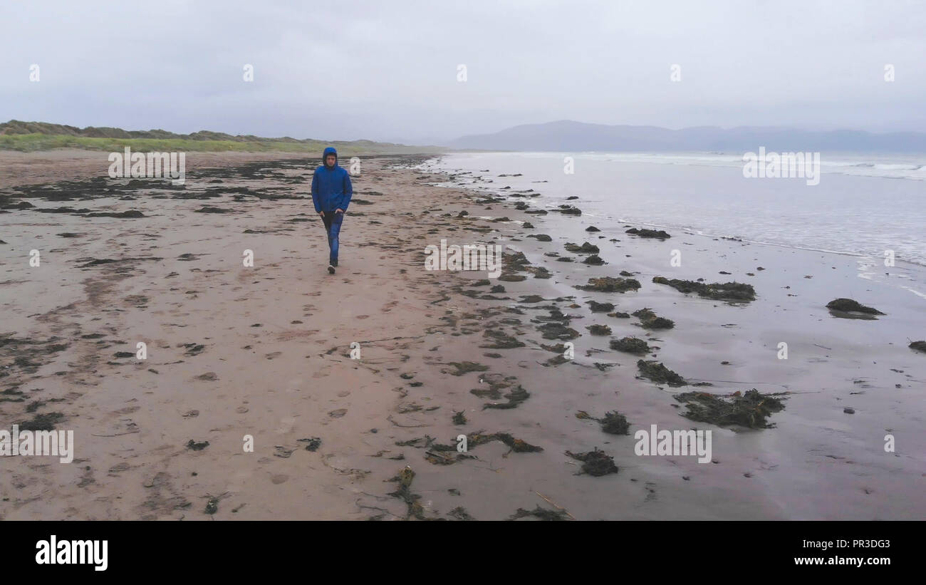 Aerial view over a young man walking along the beach Stock Photo - Alamy