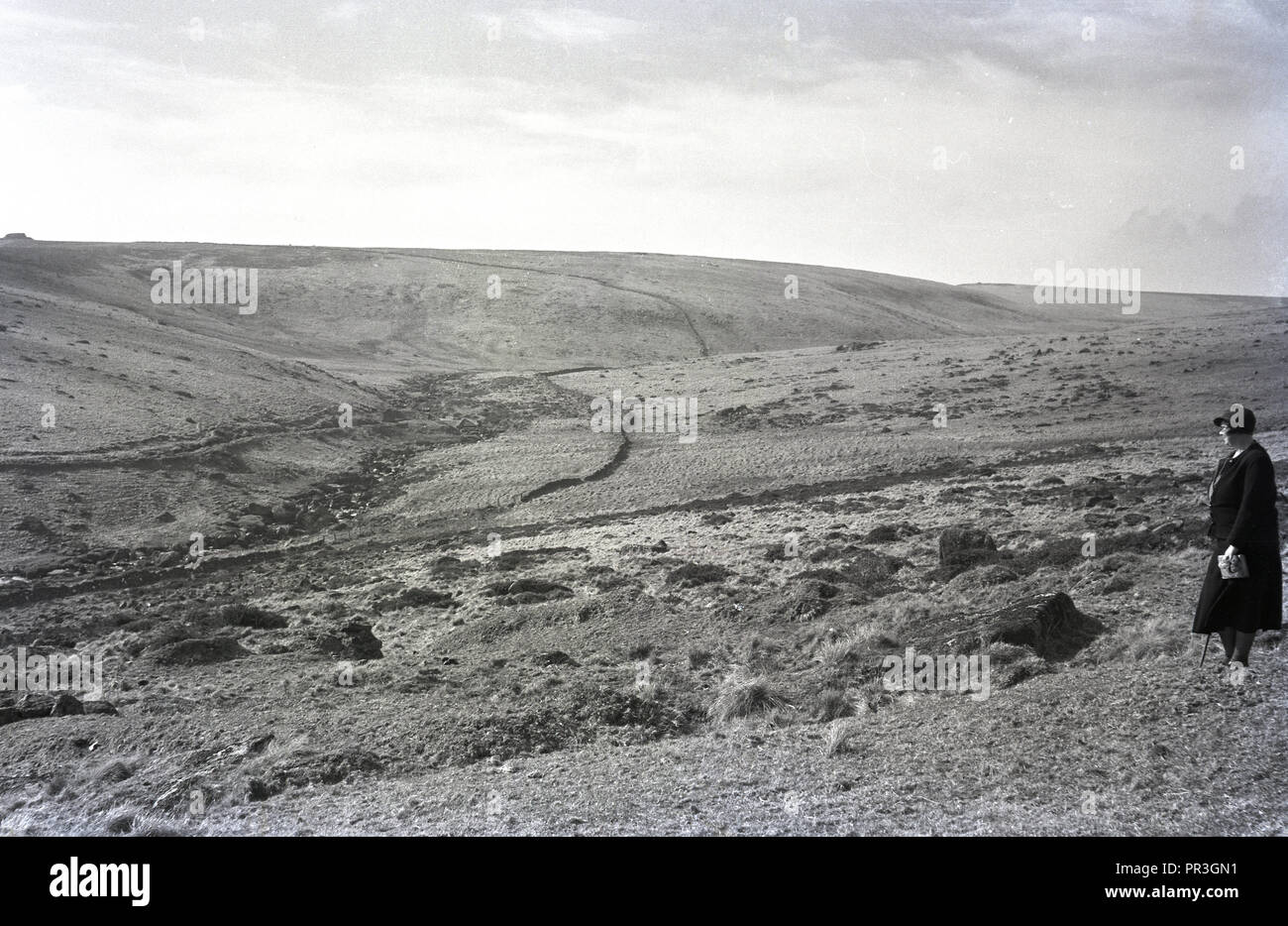 1930s, historical, a lady walker standing looking over Dartmoor national park in Devon, England, UK, a natural wild open moorland that contains many granite outcrops known as tors. Stock Photo