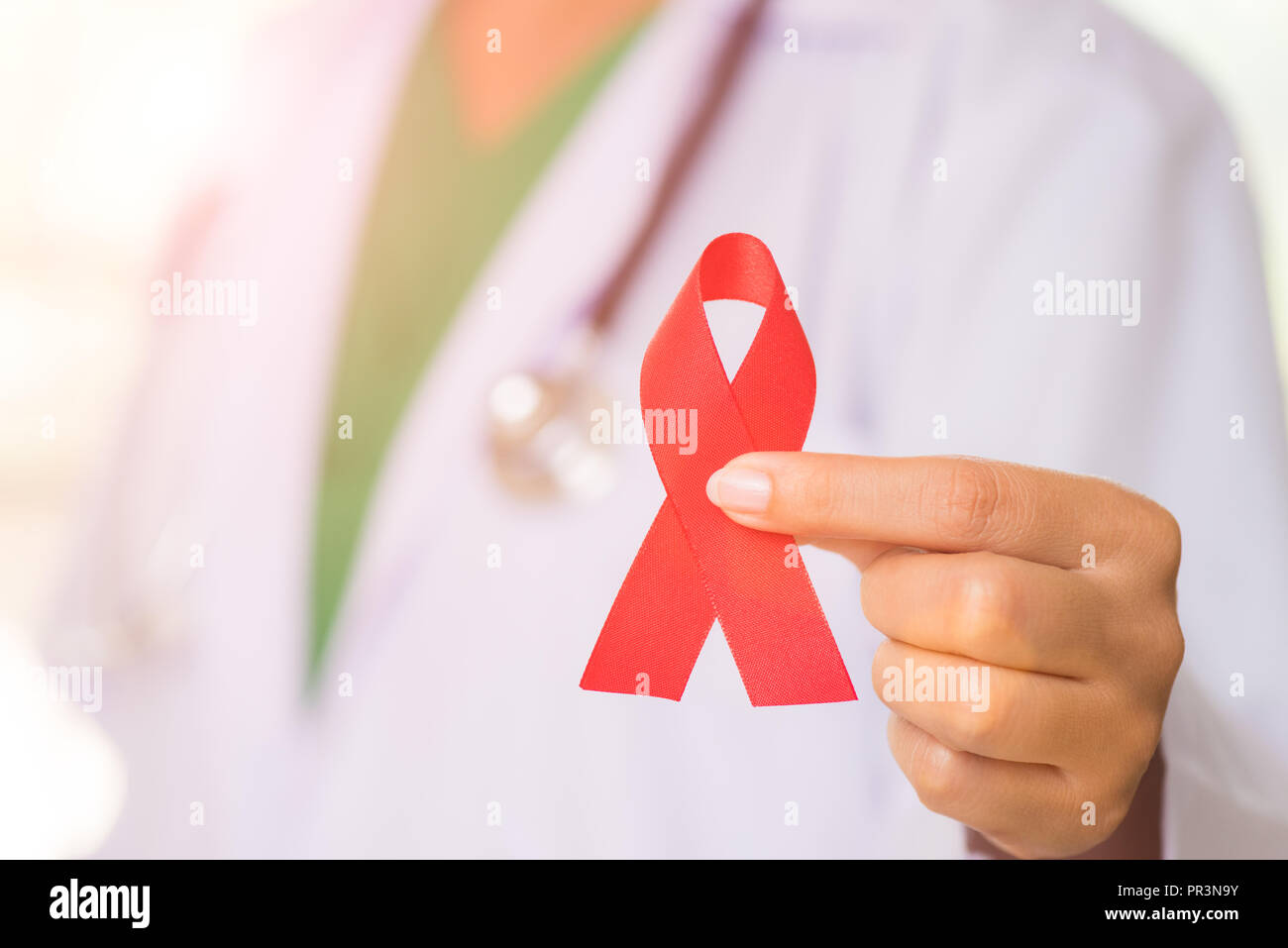 Female doctor with a stethoscope on shoulder holding red ribbon HIV ...