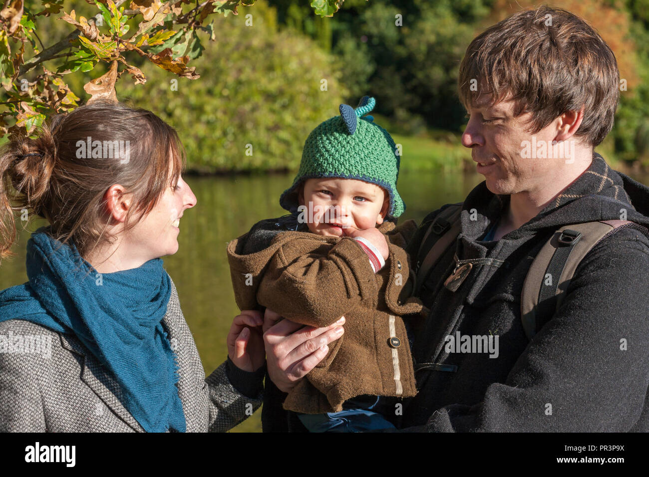 A couple and their baby son: happy smiles in Sheffield Park, East Sussex, England, UK.  MODEL RELEASED Stock Photo