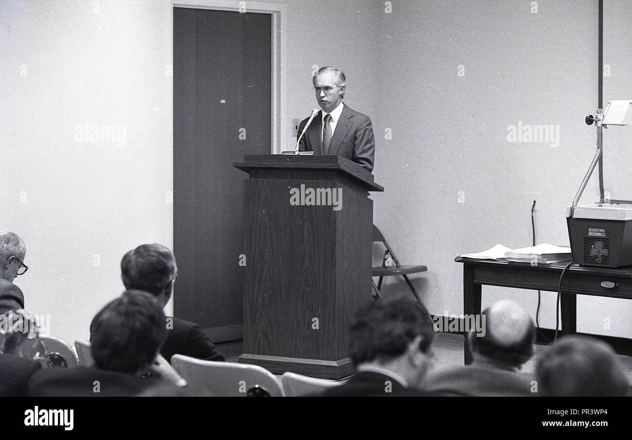A MAN AT THE PODIUM GIVING A SPEECH IN FRONT OF A GROUP OF MEN Stock ...