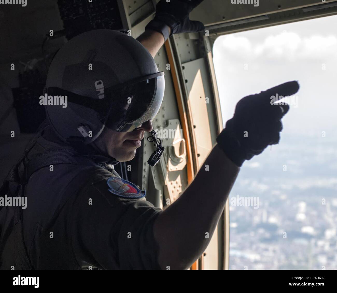 Tech. Sgt. Jonathan Lange, 374th Operations Support Squadron C-130J loadmaster, gives point commands prior to personnel jump onto the Yokota Air Base, Japan, July 28, 2017, during a training mission. The training not only allowed survival, evasion, resistance and escape specialists to practice jumping, but it also allowed the Yokota aircrews to practice personnel drops and maintaining their qualifications. Stock Photo