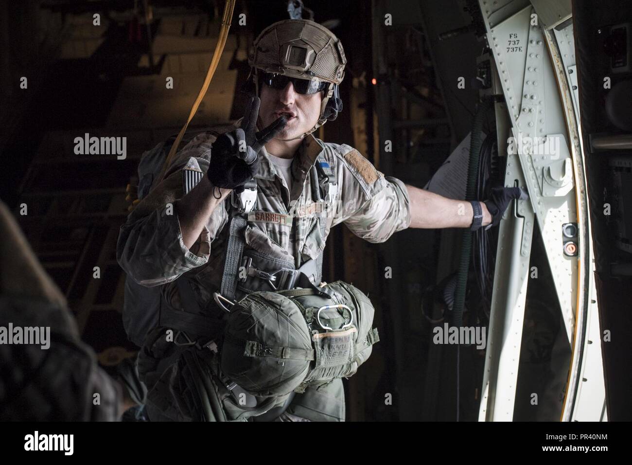 Tech. Sgt. Seth Sarrett, 374th Operations Support Squadron survival, evasion, resistance and escape specialist, gives a command prior to personnel jumping out of a C-130J Super Hercules over Yokota Air Base, Japan, July 28, 2017. Yokota SERE specialists conduct regular jump training to stay qualified and mission ready. Stock Photo